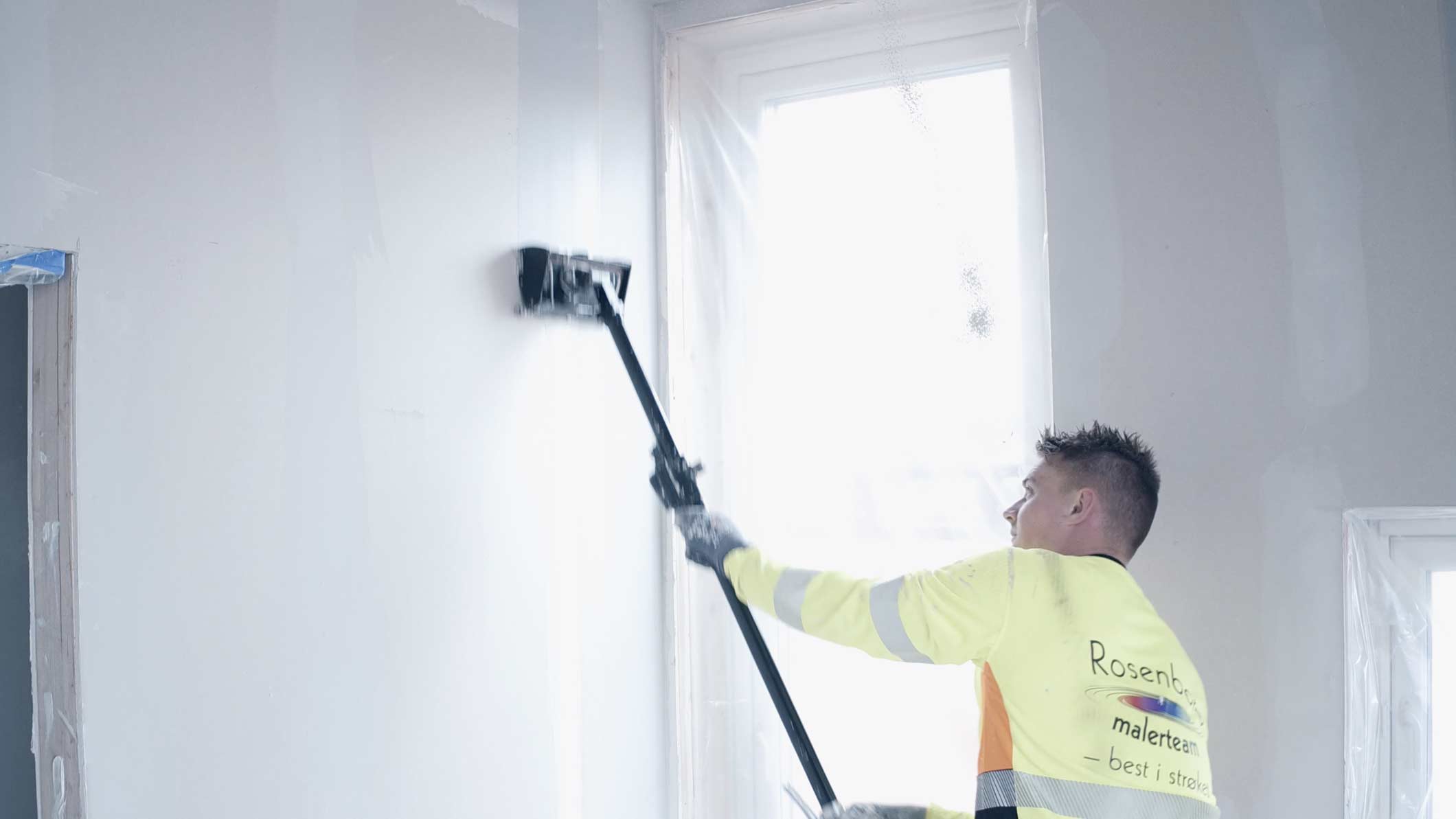 Maler fra Rosenborg Malerteam ruller en vegg innvendig